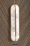 A vertical oval wall sconce with a textured, marbled off-white finish, mounted on a brown ribbed wall.