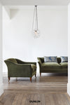 Green sofa and armchair in a room with a geometric pendant light and 'DUNLIN' branding.