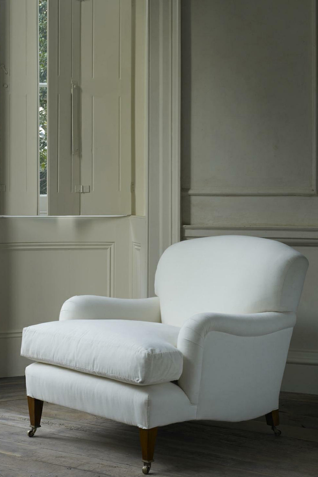 White armchair in a room with neutral walls and wooden floor.