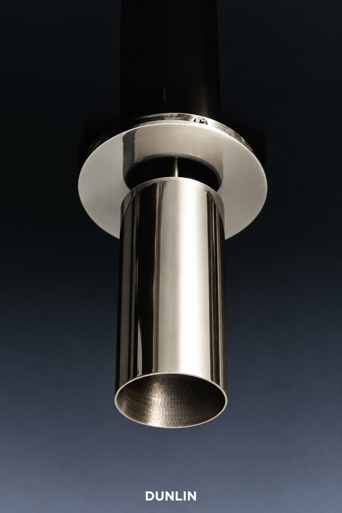 A close-up studio shot of a polished stainless steel cylindrical fixture or faucet component with a circular mounting plate, shown against a dark blue-to-black gradient background. The brand name 'DUNLIN' appears at the bottom.
