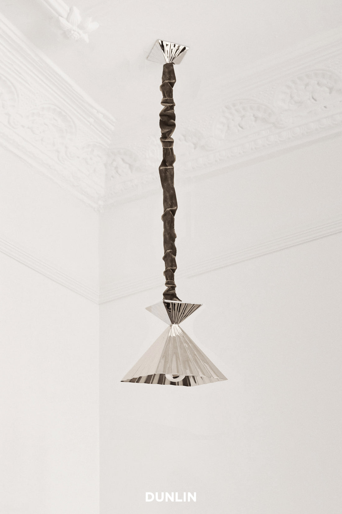 A nickel plated brass pendant light with a scrunch design, hanging from the ceiling.