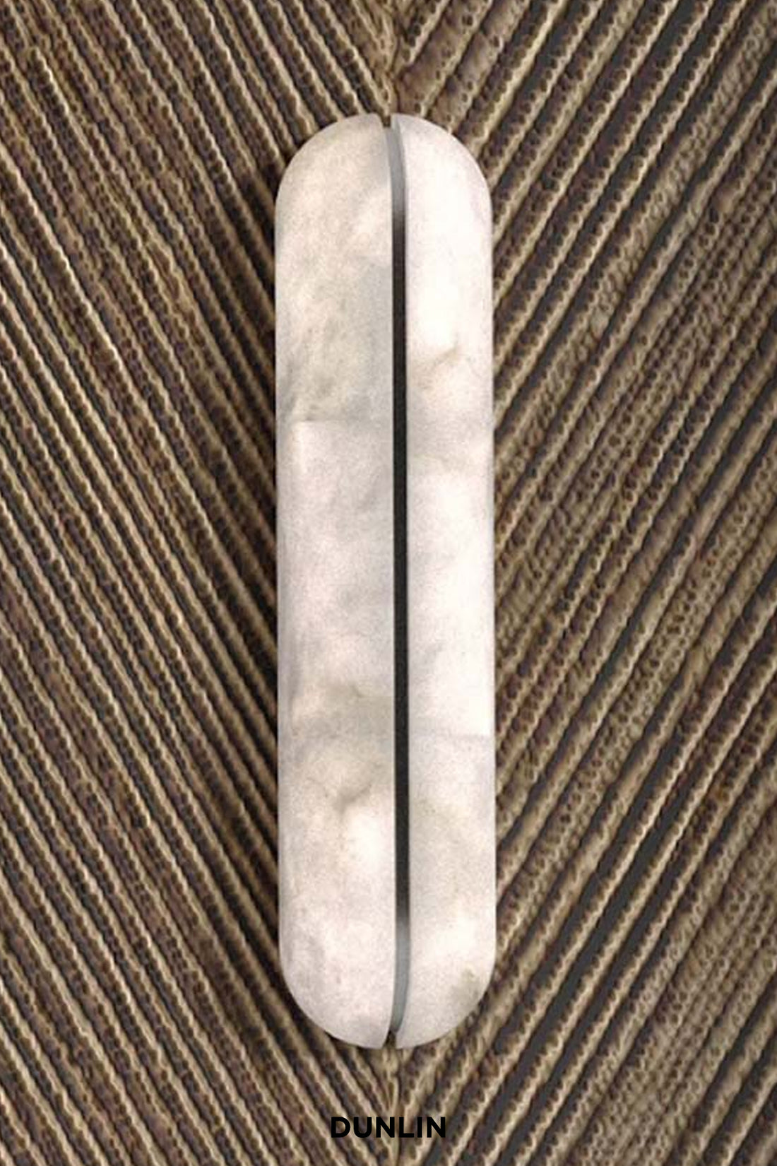 A vertical oval wall sconce with a textured, marbled off-white finish, mounted on a brown ribbed wall.