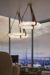 Two modern DUNLIN pendant chandeliers with white textured circular rings and brown leather straps hanging in a high-rise office lobby with a city skyline view.