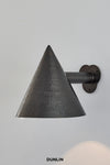 A weathered brass wall light with a conical shape and a petal wall plate, branded by Dunlin.