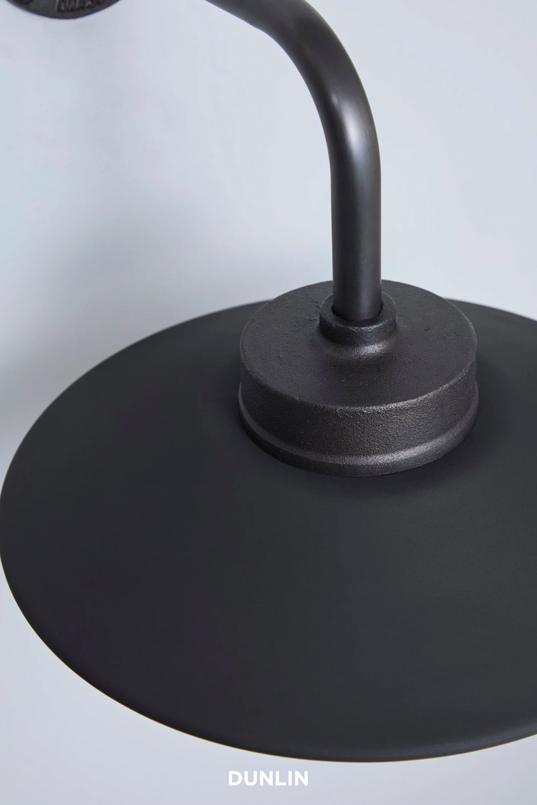 Close-up of a black metal lamp shade and curved stem with the brand name DUNLIN at the bottom.