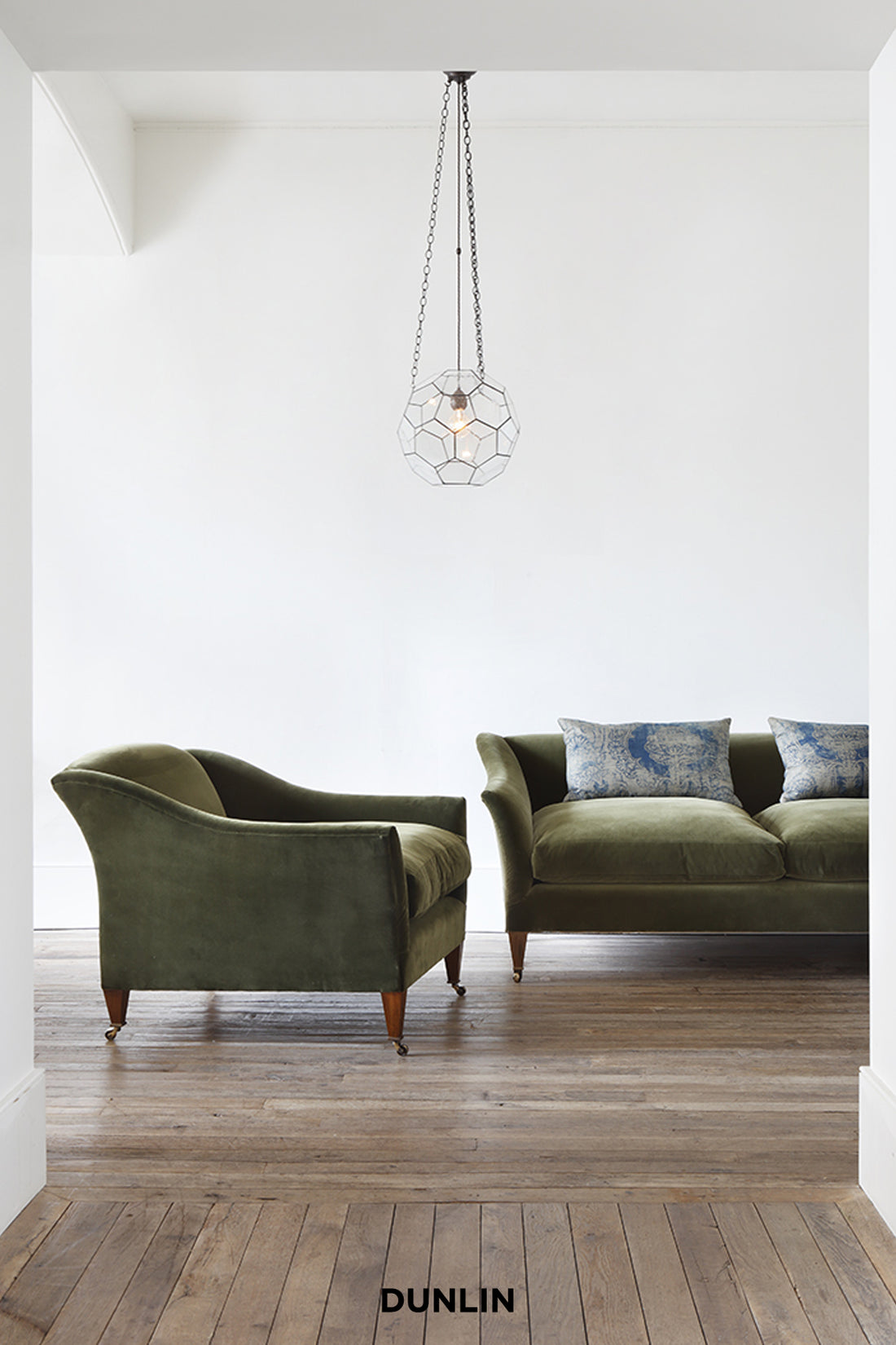 Green sofa and armchair in a room with a geometric pendant light and 'DUNLIN' branding.