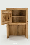 A rustic wooden storage cabinet with a hinged door on the left, shown open to reveal two interior shelves. The cabinet has a natural oak finish with prominent wood grain and knots, set against a plain light gray background.