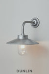 Galvanised steel Chelsea Outdoor Wall Light by Davey Lighting with curved arm, wide reflector and clear glass shade.