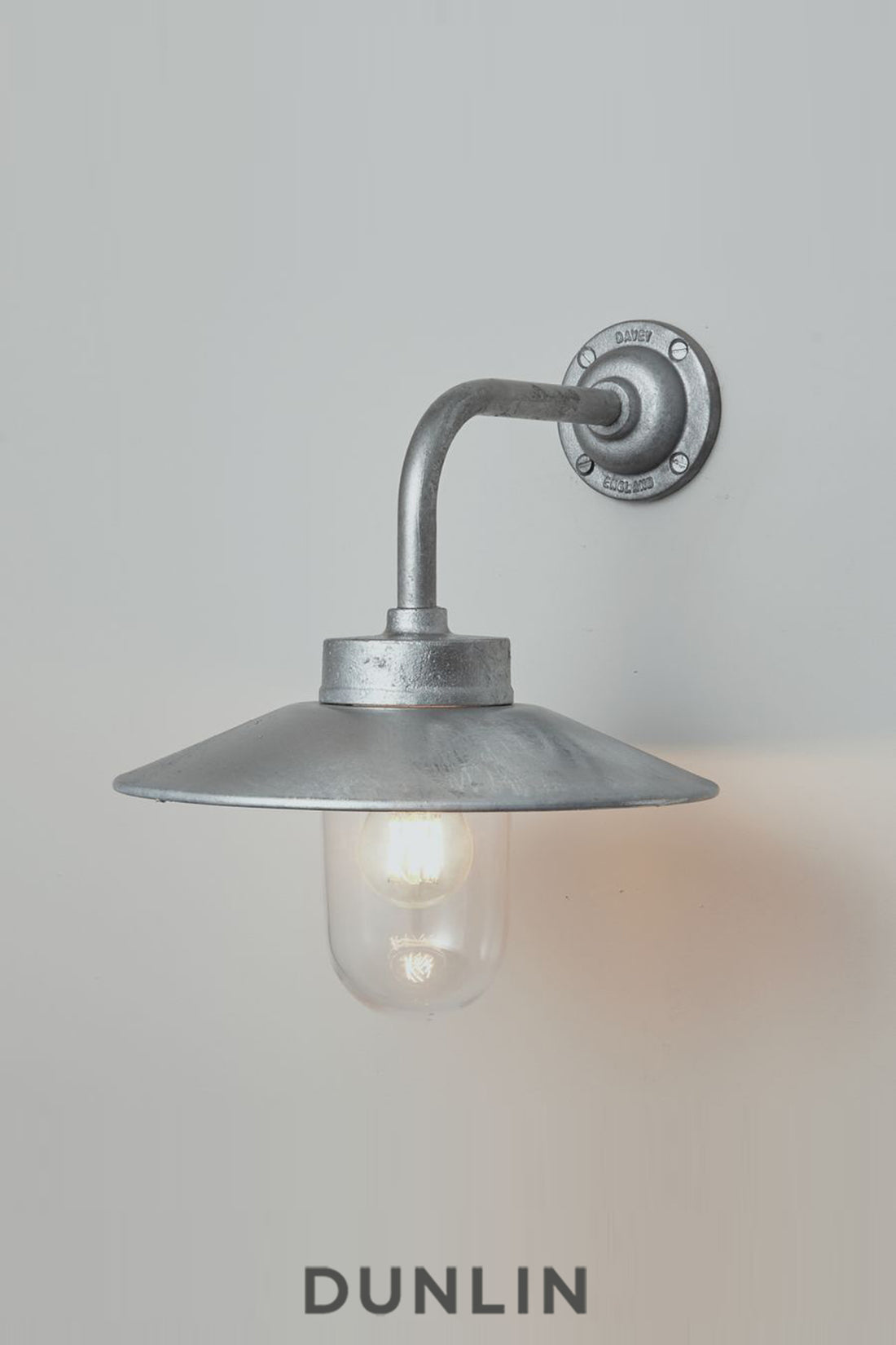 Galvanised steel Chelsea Outdoor Wall Light by Davey Lighting with curved arm, wide reflector and clear glass shade.