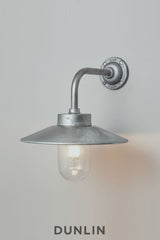 Galvanised steel Chelsea Outdoor Wall Light by Davey Lighting with curved arm, wide reflector and clear glass shade.